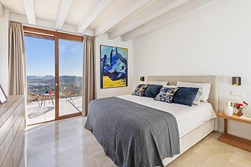 A bedroom with a large bed and a painting on the wall