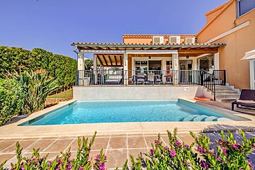 A house with a large swimming pool in front of it