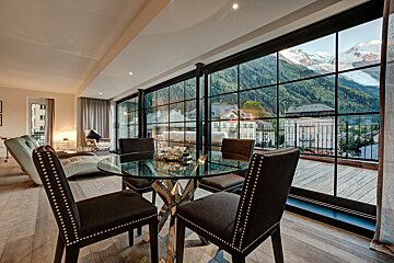 A room with a table and chairs and a view of mountains