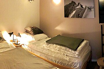 A bedroom with two beds and a painting on the wall