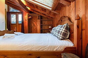 A wooden bedroom with a bed and a window