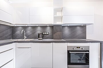 A kitchen with white cabinets and a stainless steel oven