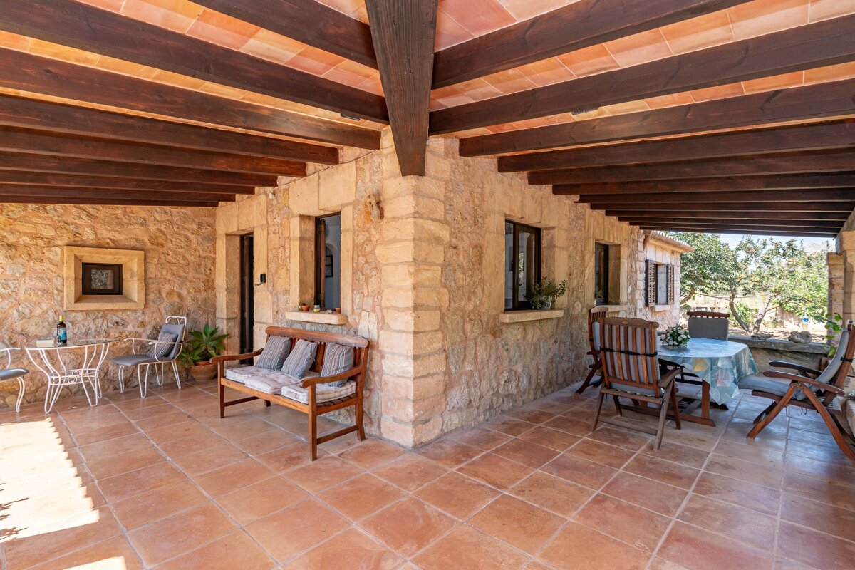 A patio with a table and chairs under a wooden ceiling