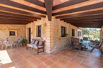 A patio with a table and chairs under a wooden ceiling