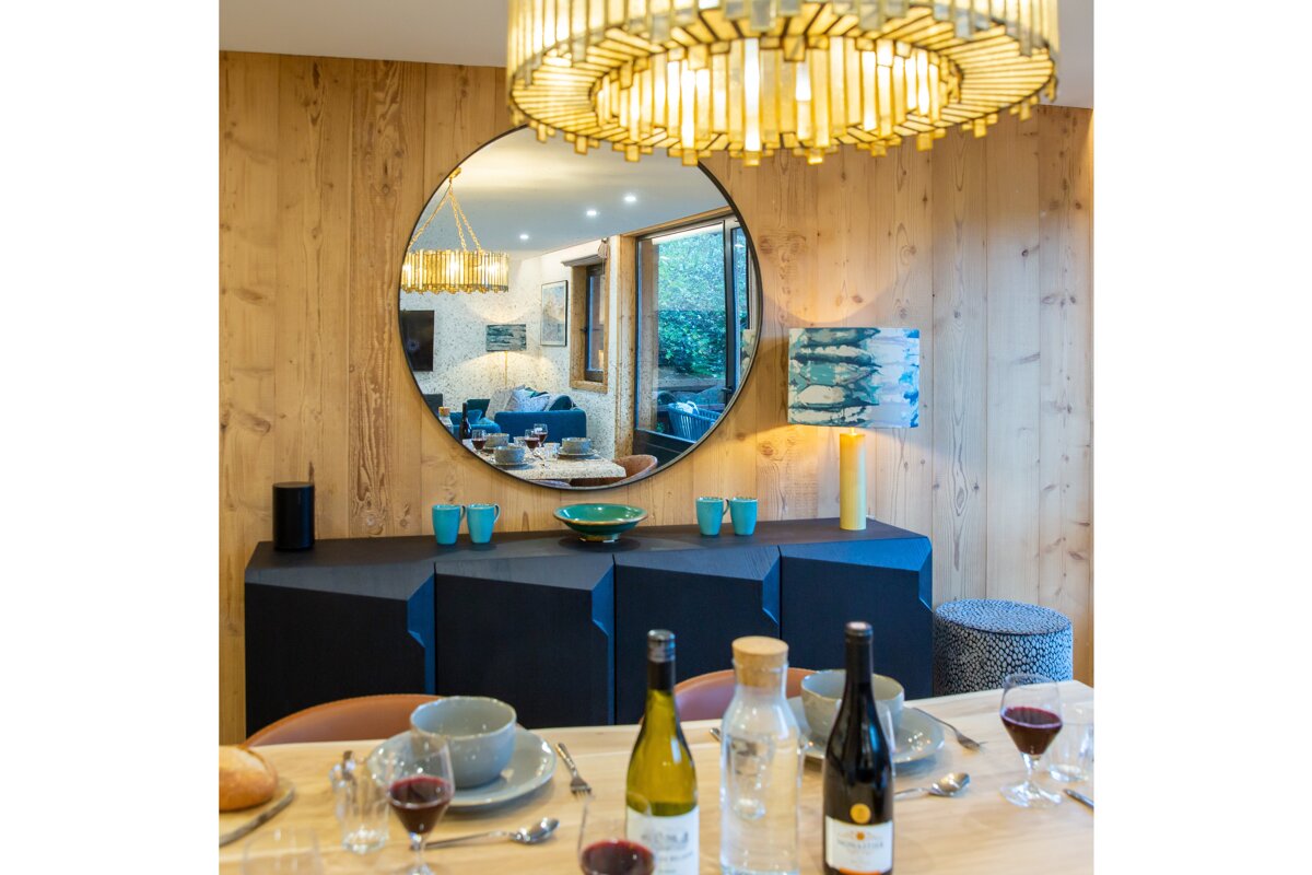 A bottle of wine sits on a table in front of a large mirror