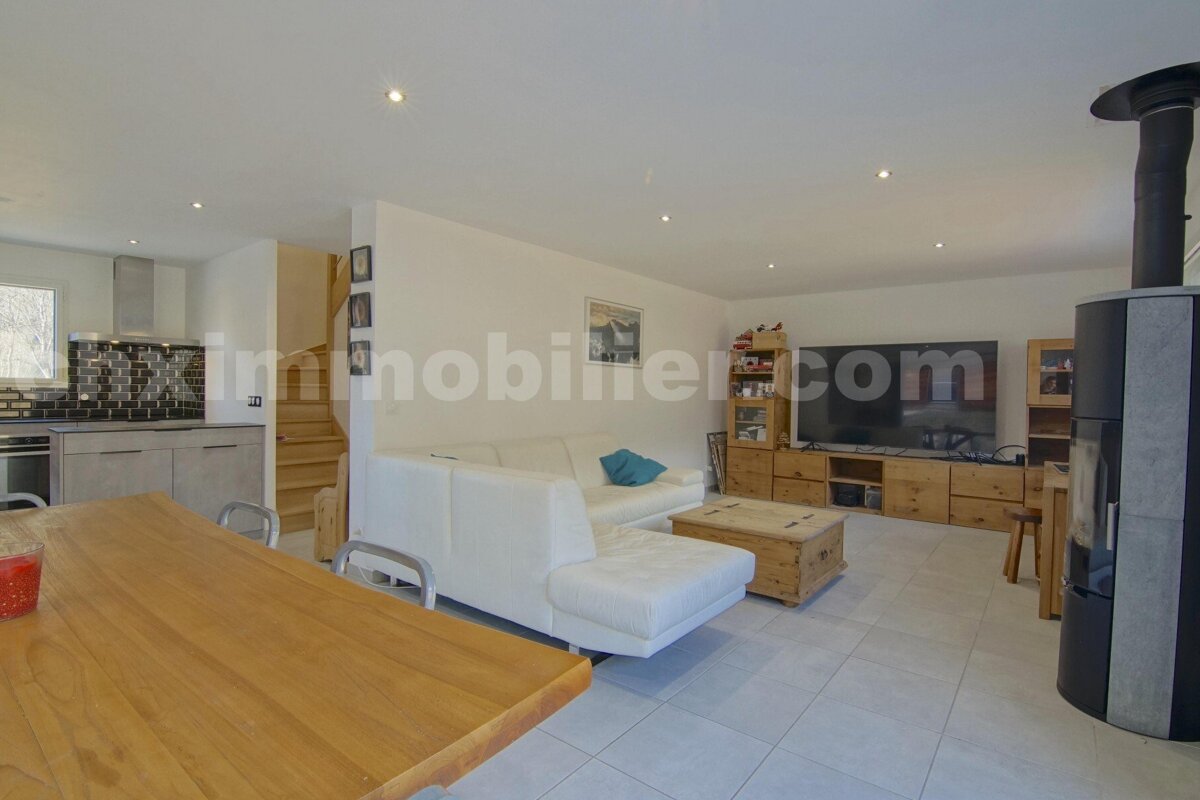 A living room with a couch and a television with the website immobilier.com in the corner