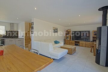 A living room with a couch and a television with the website immobilier.com in the corner