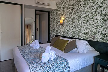A hotel room with a bed and slippers on it