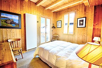 A bedroom with a bed a chair and a lamp