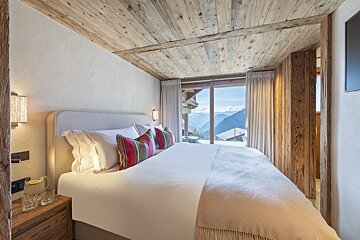 A bedroom with a large bed and a view of the mountains