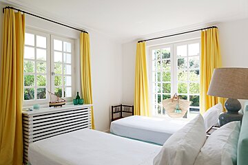 A bedroom with two beds and yellow curtains