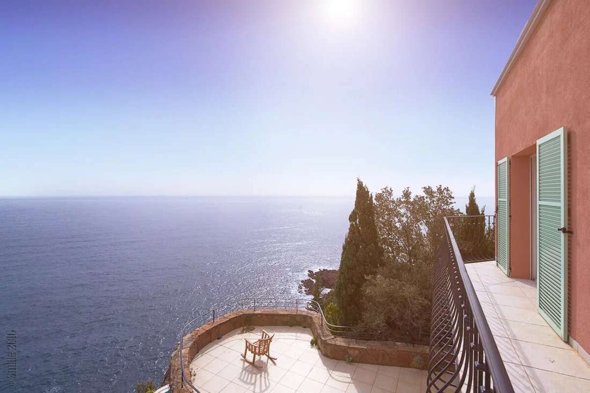 A rocking chair sits on a balcony overlooking the ocean