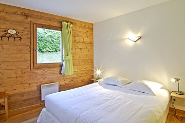 A bedroom with wood paneling and a white bed