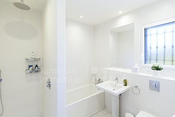 A bathroom with a sink a bathtub and a window with an advertisement for ansson 's immobilier