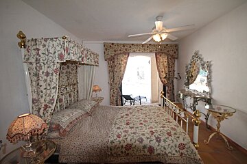 A bedroom with a canopy bed and a ceiling fan