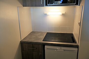A small kitchen with a stove top oven and a beko dishwasher