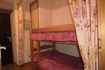 A bunk bed in a room with a pink curtain