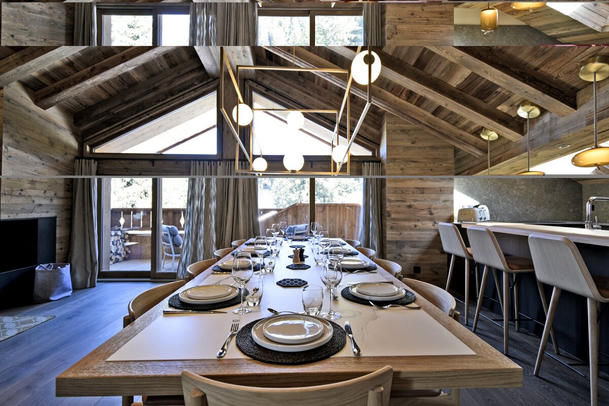 Elegant dining area in a wooden chalet, featuring a long set table, vaulted ceiling with exposed beams, and modern lighting.