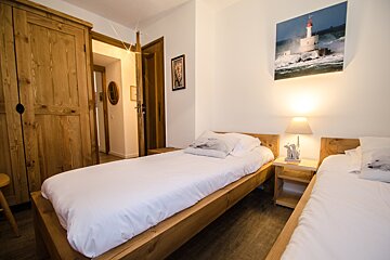 A bedroom with two beds and a picture of a lighthouse on the wall