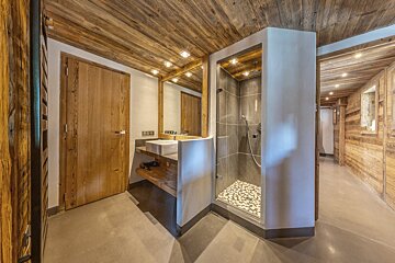 Rustic chalet bathroom with wooden ceilings, a vessel sink vanity, and a modern walk-in shower.