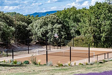 A tennis court with a volleyball net and a basketball hoop