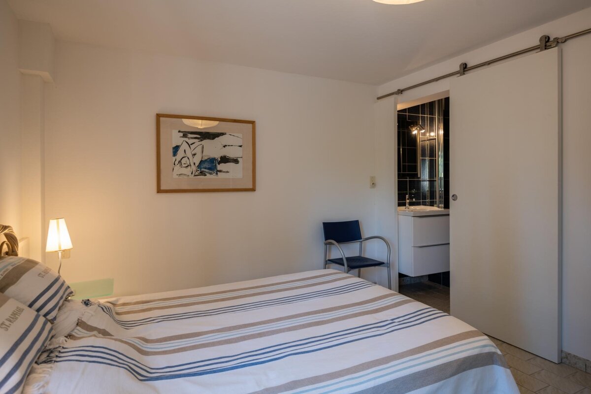 A bedroom with a sliding barn door leading to a bathroom