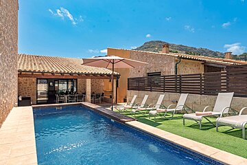 A swimming pool with chairs and an umbrella in front of a house