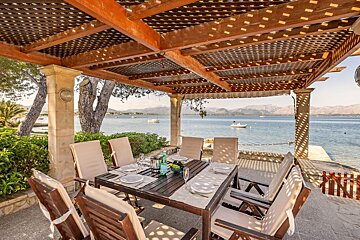 A table and chairs under a pergola overlooking the ocean