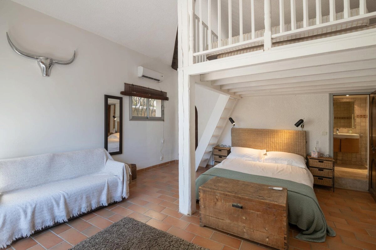 A bedroom with a couch a bed and a staircase