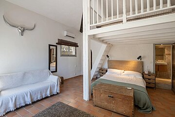 A bedroom with a couch a bed and a staircase