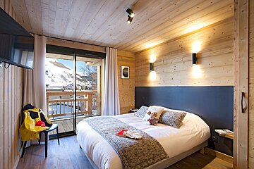 A bedroom with a large bed and a sliding glass door