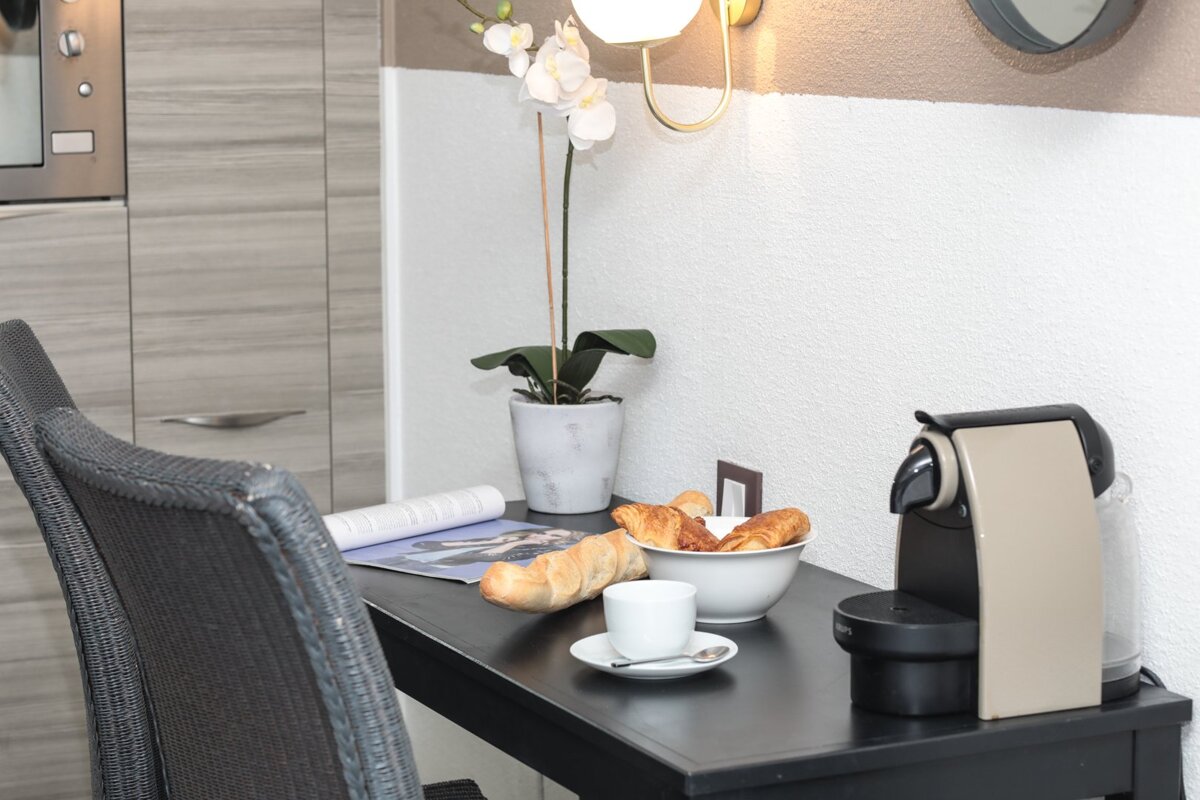 A nespresso machine sits on a table next to a bowl of croissants