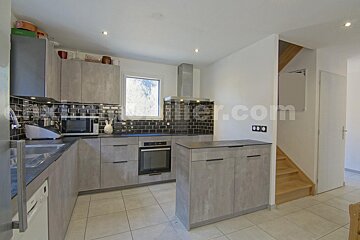 A kitchen with a staircase and a website called keller.com