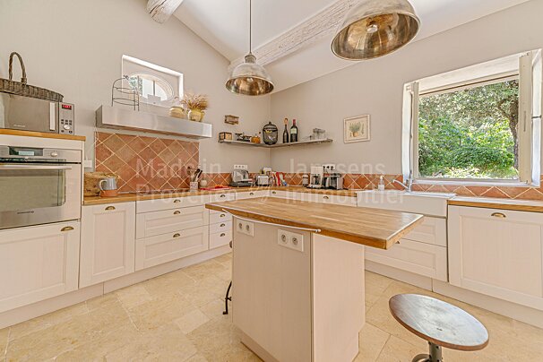 A kitchen with white cabinets and a wooden island with the word madein on the bottom