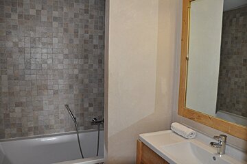 A bathroom with a tub and a sink and a mirror