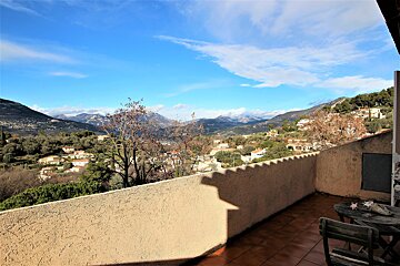 A balcony overlooking a valley with mountains in the background