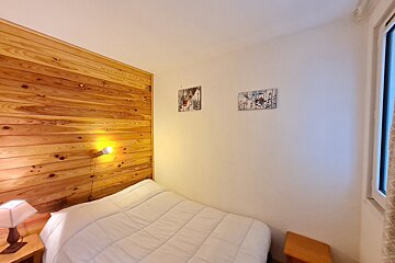 A bedroom with a bed and two paintings on the wall