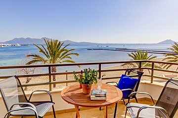 A table with a book on it sits on a balcony overlooking the ocean