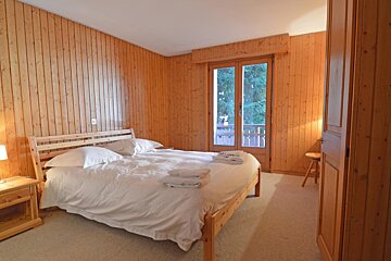 A bedroom with wood paneling and a bed with white sheets