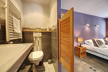 A bathroom next to a bedroom with purple walls