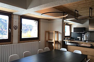 A kitchen with a black table and white chairs