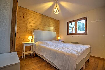 A bedroom with wood paneled walls and a white bed