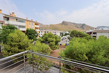 A balcony overlooking a residential area with mountains in the background