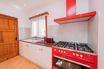 A kitchen with a red stove and a clock that says 12:58