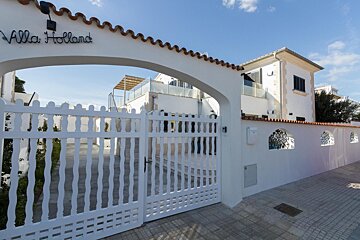 Villa holland is written on a white sign above a white gate