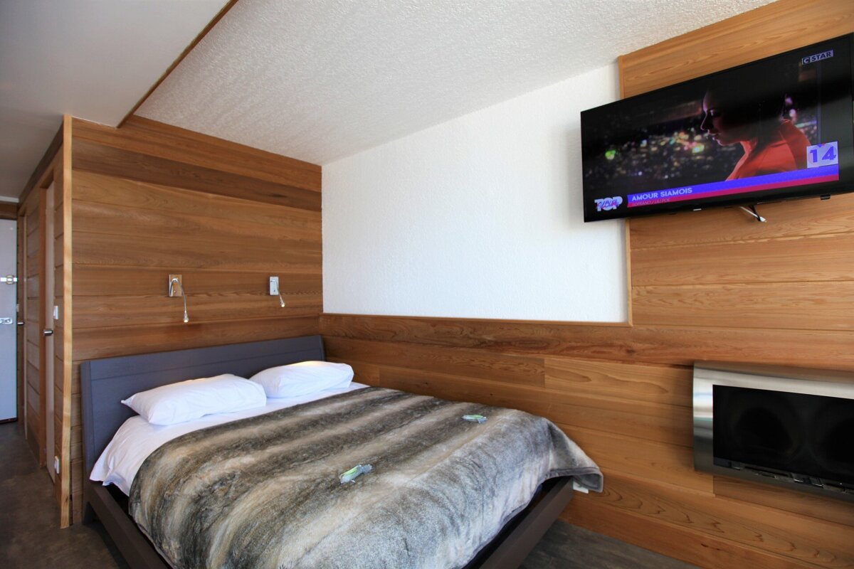 A bedroom with a bed and a flat screen tv that says top