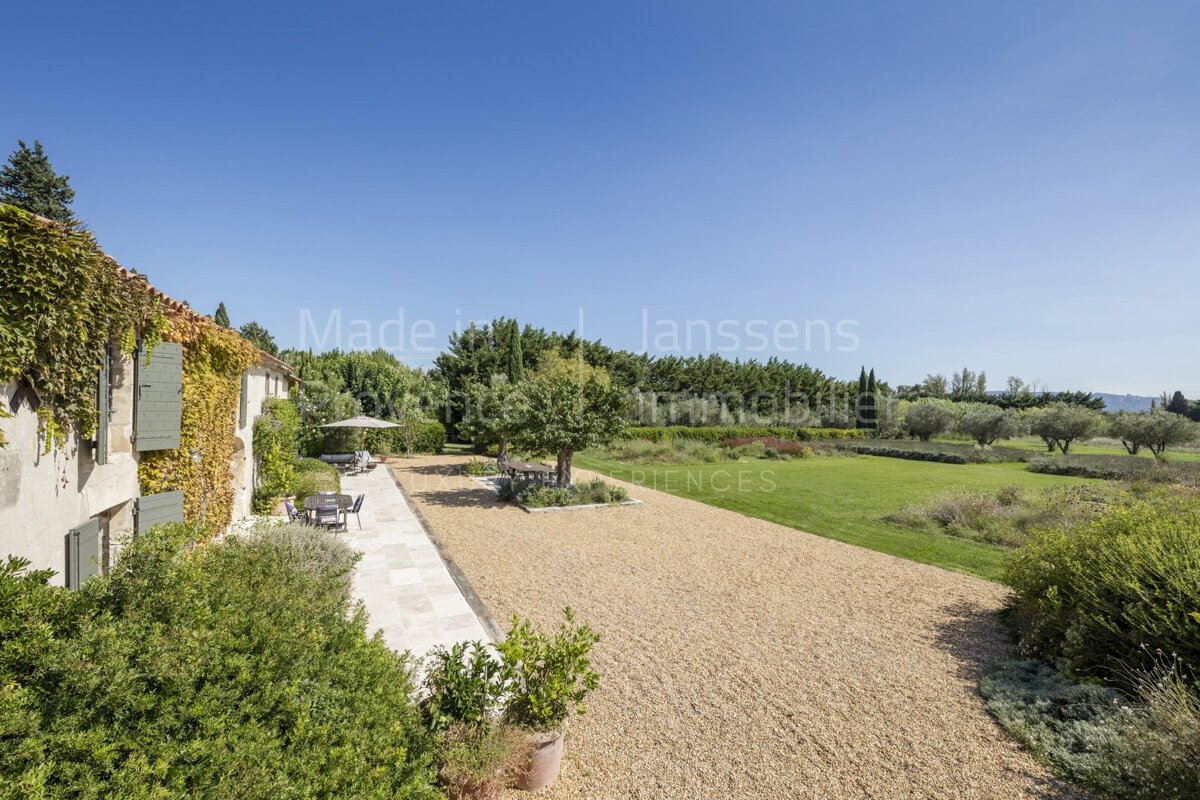 A gravel driveway leading to a house with the word lanssens on the bottom