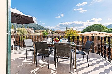 A table and chairs on a balcony with mountains in the background