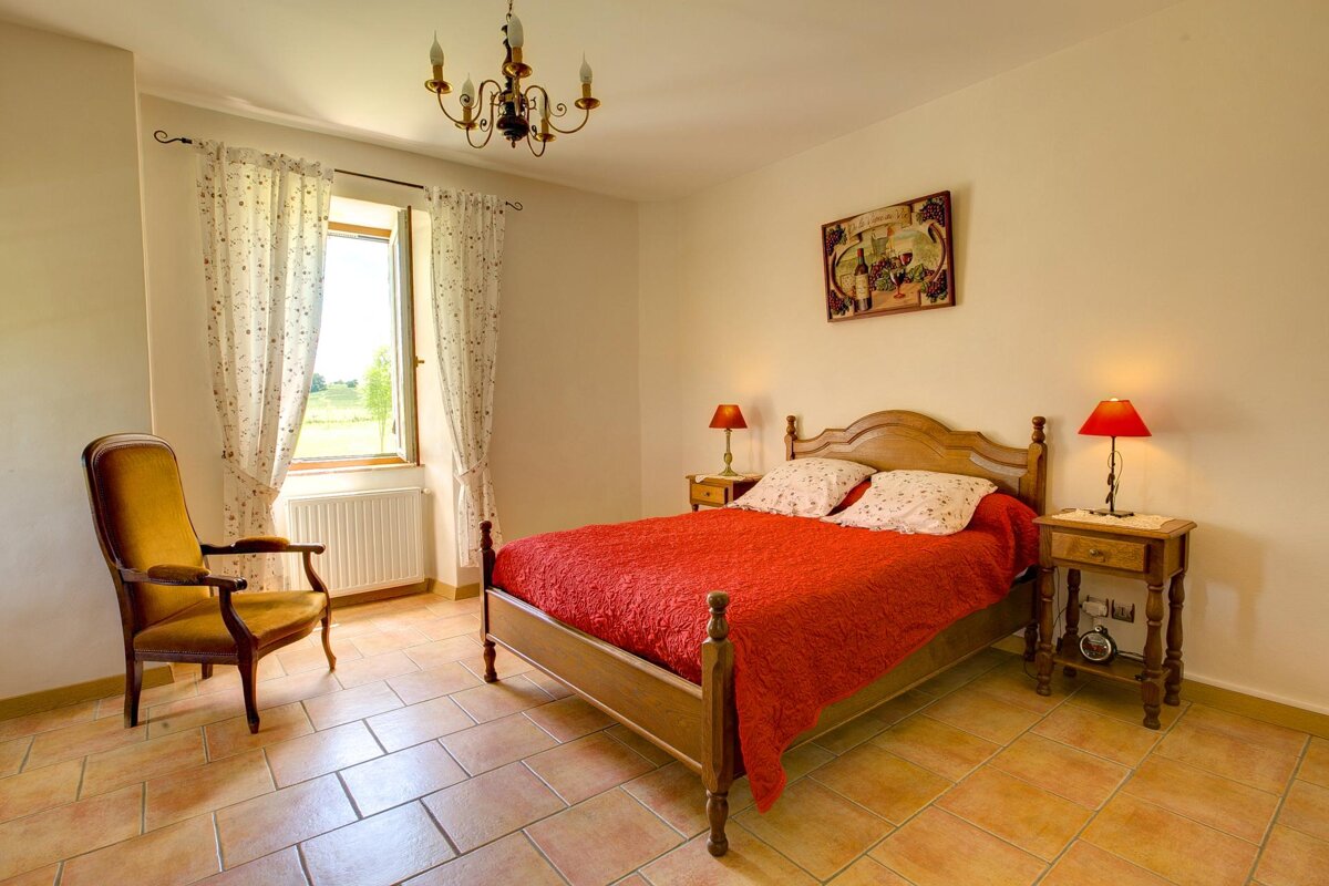 A bedroom with a red bed and a yellow chair