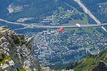 A paraglider is flying over a small town in the mountains